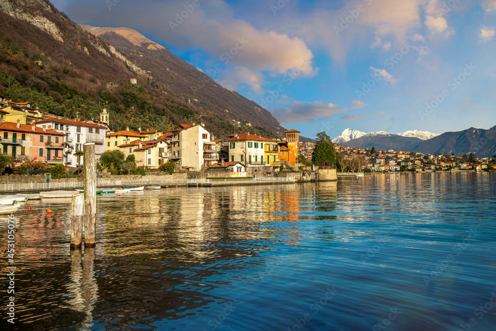 Amazing scene with houses  in some village  on left coast  of  Lake Como and snow-capped peaks in the Alps at distance