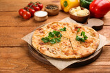 Delicious khachapuri with cheese, parsley and vegetables on wooden table