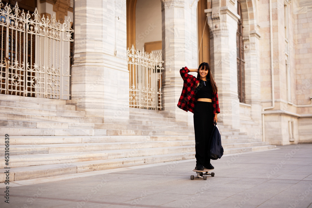 Portrait of young beautiful girl with skateboard. Happy smiling woman relaxing outdoors.