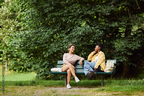 Female friends sitting on bench and talking