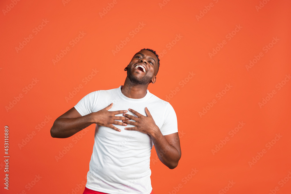 Naklejka premium Happy African young man in casual clothes isolated on red color studio background. Concept of human emotions, facial expression, youth, feelings, ad.