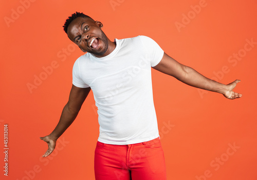 Portrait of African young man in casual clothes isolated on red color studio background. Concept of human emotions, facial expression, youth, feelings, ad.