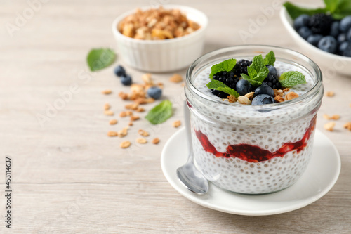 Delicious chia pudding with berries and granola on wooden table. Space for text