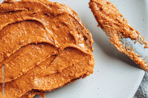 Close-up of peanut butter on toasted bread on light gray plate. Food background. photo