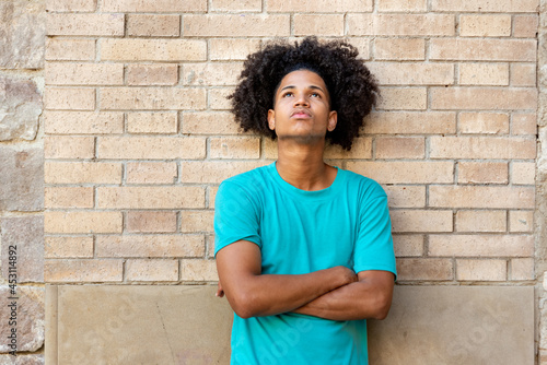 Portrait of young afro latin man against a brick wall