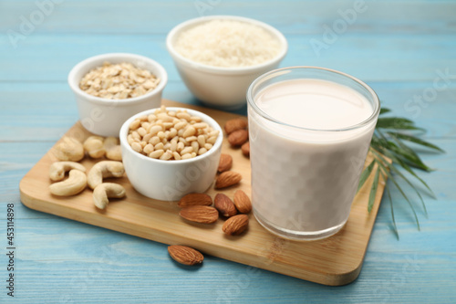 Vegan milk and ingredients on light blue wooden table, closeup