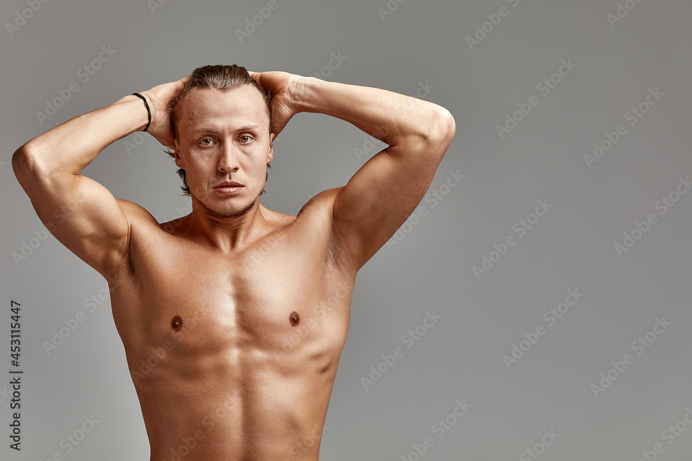 Fototapeta premium Portrait of an athlete swimmer on a gray background, in excellent resistive shape, charismatic, adult, edited photo, bright smile, straightens hair, gray background, copies of space.
