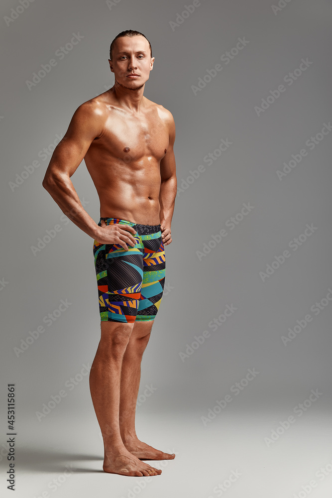 A portrait of an athlete in swimming trunks, in excellent athletic form, charismatic, adult, self-confident and charged to win.