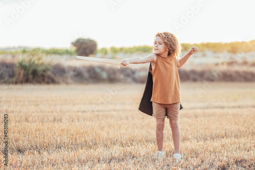 Ethnic child in knight costume with sword in field photo