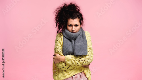 Fotografi displeased woman freezing in sweater and scarf while looking at camera isolated
