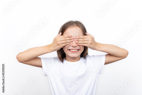 Cute little child girl closes her eyes with her hand on white background. I see nothing.
