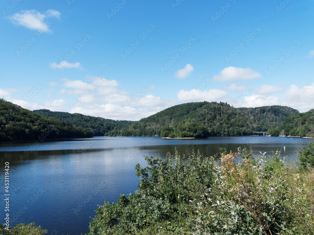 Paysage de lac en Auvergne - Patrimoine et nature des Combrailles. Plan d'eau et barrage des Fades-Besserve sous un ciel bleu d'été