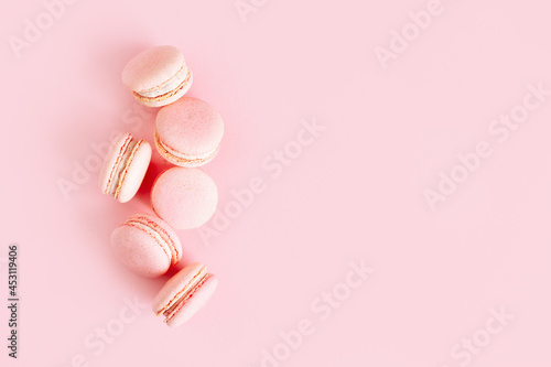 Tasty french macarons on a pink pastel background.