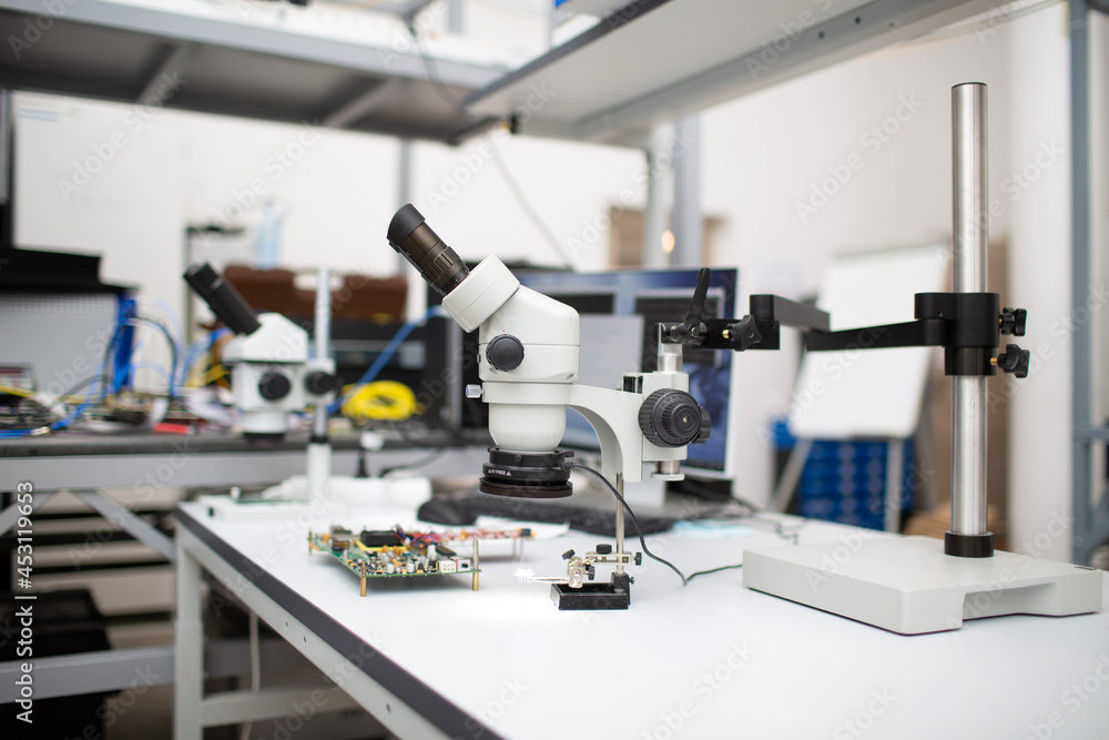 Microscope and electronic board in Scientific research tech Laboratory on table.