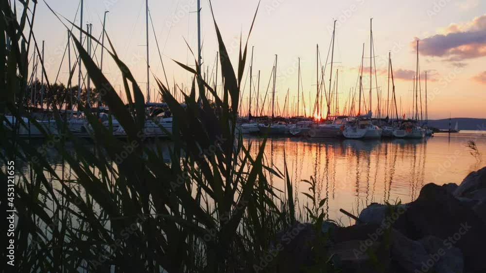 Slow low angle trucking shot of sailboats in marina at sunset Slow low angle trucking shot of sailboats in marina at sunset