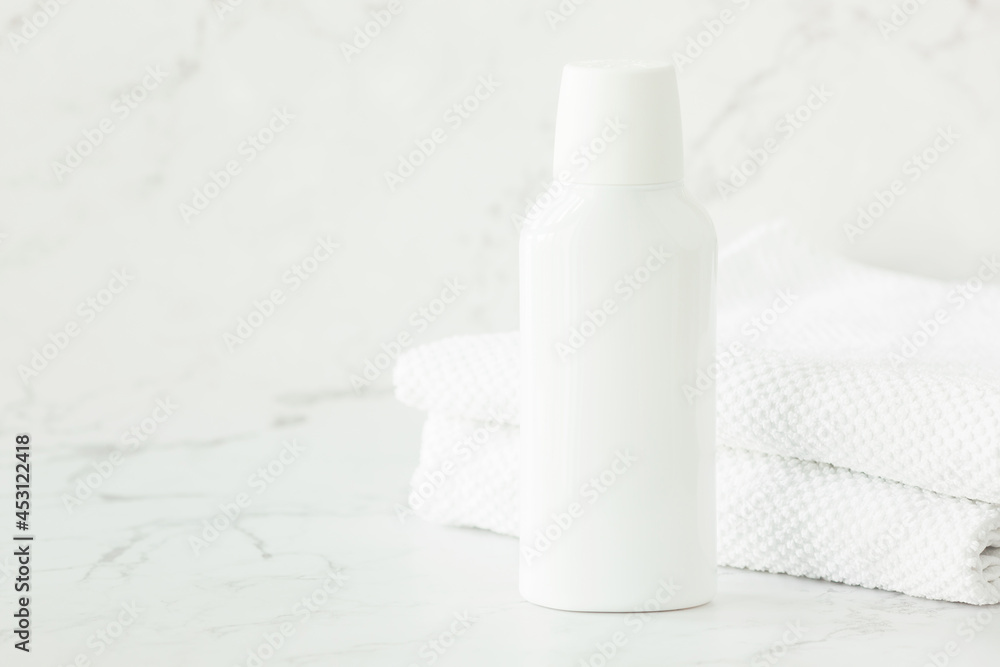 Empty white cosmetic container, jar, and towels on shelf in bathroom. Cosmetics for face and body care. Copy space.