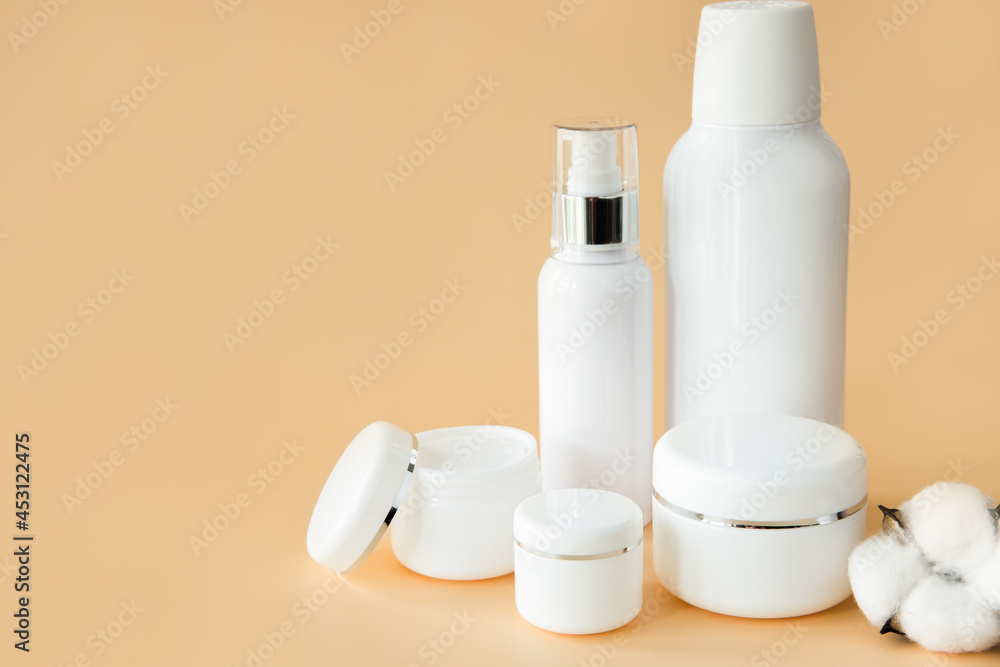 Empty white cosmetic containers and bottles on a beige background. A set of cosmetics for face and body care. Copy space. Empty white cosmetic containers and bottles on a beige background. A set of cosmetics for face and body care. Copy space.