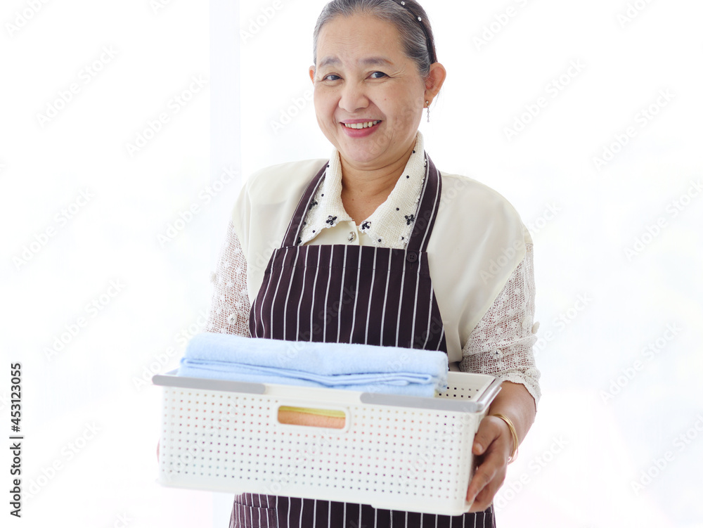 Portrait of Happy smiling Asian senior elderly woman housewife carrying clothes basket for doing laundry on white background, grandma doing housework and cleaning clothes at house Portrait of Happy smiling Asian senior elderly woman housewife carrying clothes basket for doing laundry on white background, grandma doing housework and cleaning clothes at house