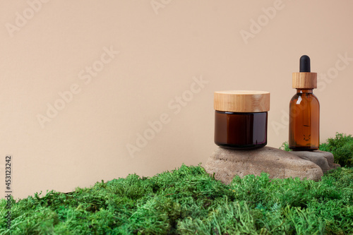 Skin care products on pastel beige background with moss, wood. Close up, copy space.