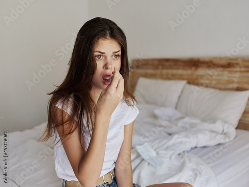 woman in bed checking the temperature with a thermometer in her mouth