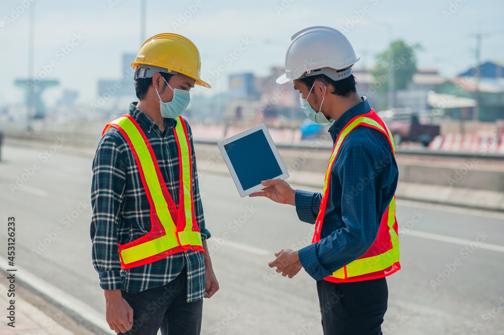 Two engineer wear face mask using tablet work outdoor on site survey Two engineer wear face mask using tablet work outdoor on site survey