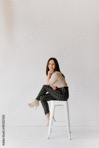 Studio shot of young woman sitting on stool photo
