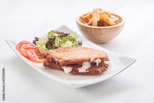 steak filled cheese and ham (san jacobo, librito) with salad and potatoes chips photo