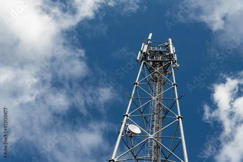 Bottom perspective pov of modern metal steel mobile 5g network wireless telecom tower against clear blue sky background on bright day. Microwave signal broadband equipment base line station mast