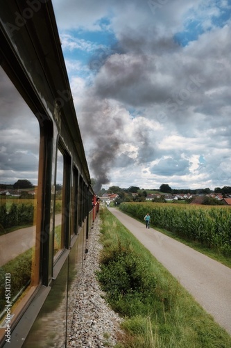 Alte historische Eisenbahn mit einer Dampflokomotive davor fährt durch schwäbische Landschaft