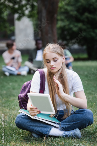 Student using digital tablet on lawn outdoors