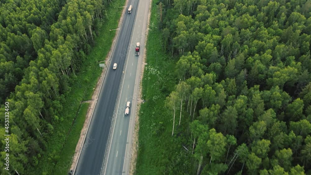 Aerial view of cars and trucks driving fast along a suburban highway. Transportation of goods as a business in the modern world. The concept of transport links between settlements, cities. UHD 4K. Aerial view of cars and trucks driving fast along a suburban highway. Transportation of goods as a business in the modern world. The concept of transport links between settlements, cities. UHD 4K.