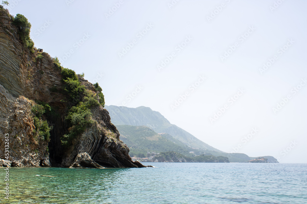 Rocky seaside coast. Boulders are standing in the beautiful water. Group of large stones against the blue sky. Big stone on the background of the sea. Rocky seaside coast. Boulders are standing in the beautiful water. Group of large stones against the blue sky. Big stone on the background of the sea.