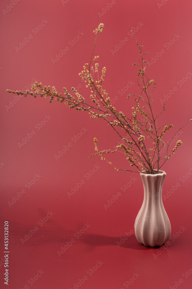 small porcelain vase with flowers on a red background.