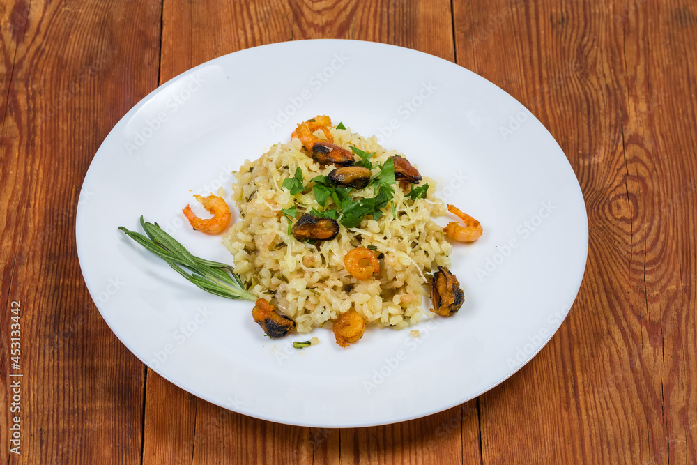 Serving of risotto with seafood on dish on rustic table Serving of risotto with seafood on dish on rustic table
