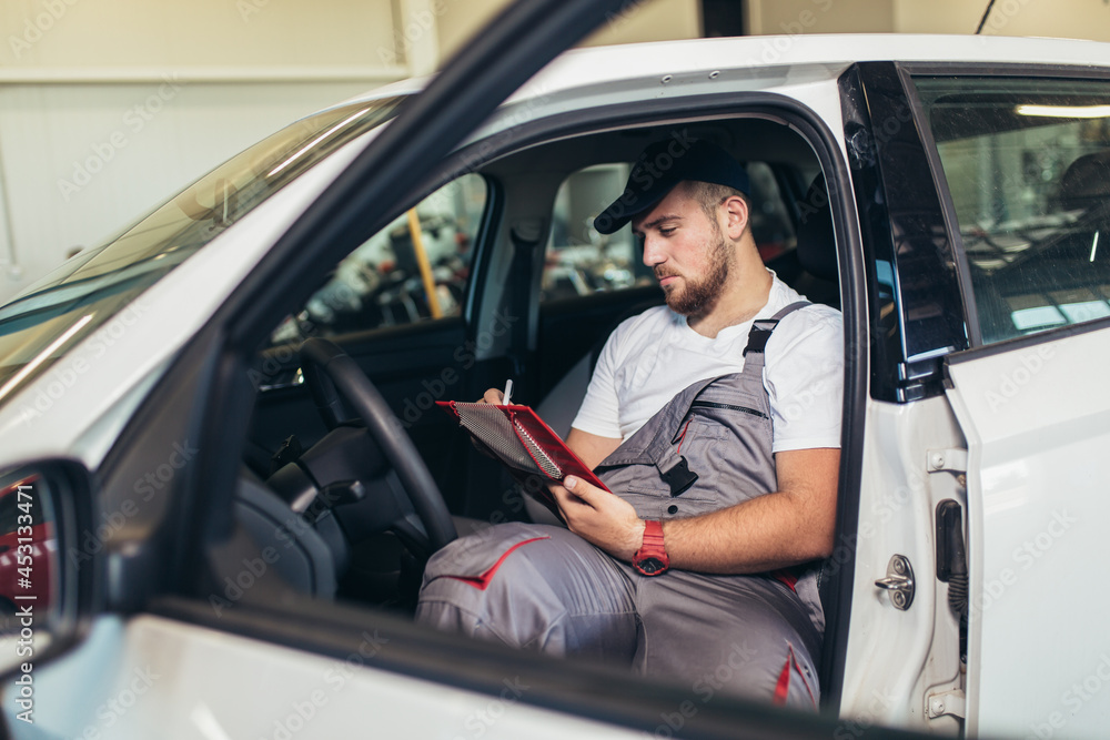 Man writing on a clipboard in a garage. Man writing on a clipboard in a garage.