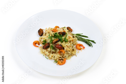 Serving of risotto with seafood on dish on white background