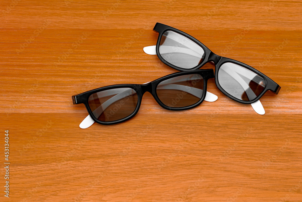 3d glasses from the cinema are very similar to sunglasses lying on a wooden surface 3d glasses from the cinema are very similar to sunglasses lying on a wooden surface