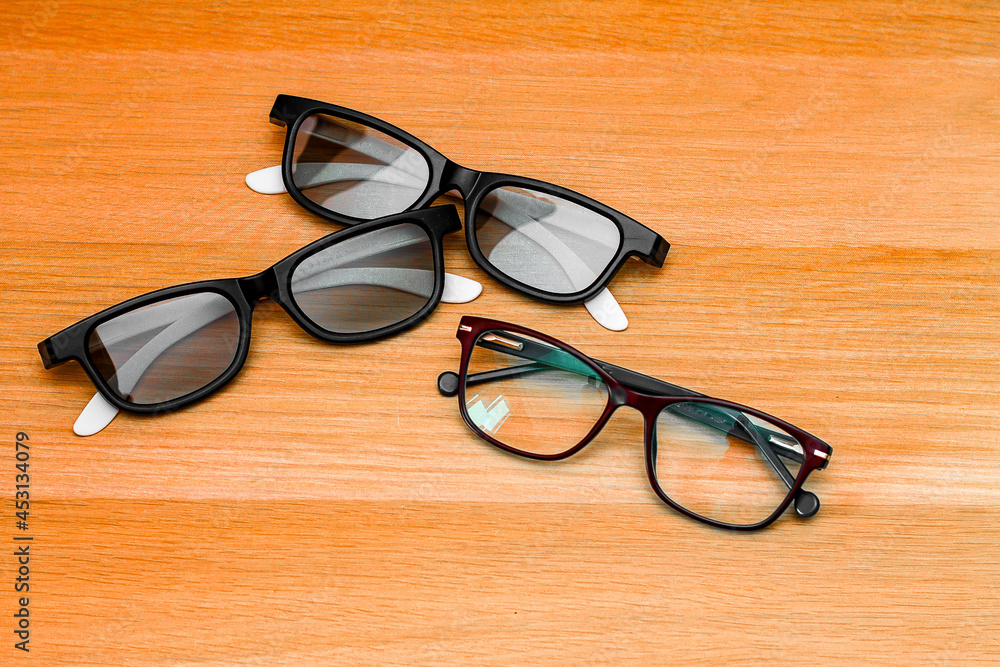 on the wooden surface, next to modern sunglasses with a 3d effect, there are simple eyeglasses for vision on the wooden surface, next to modern sunglasses with a 3d effect, there are simple eyeglasses for vision