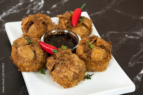 A serving of tauhu bergedil, a famous Malaysian dish with spicy soy sauce as dips. Blurred background