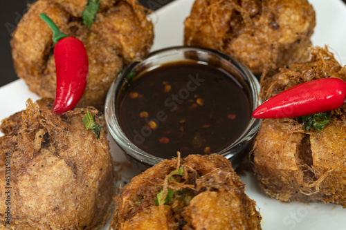 A close-up of tauhu bergedil, a famous Malaysian dish with spicy soy sauce as dips. Blurred background