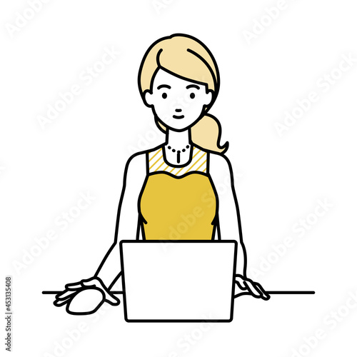 デスクで座ってPCを使っているドレスの女性