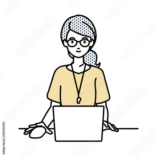 デスクで座ってPCを使っている教師の女性