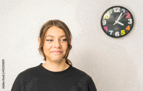 Portrait of a pretty European teenage girl on a light background, smiling, looking at camera. a happy schoolgirl