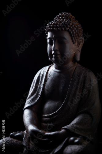 Meditating Buddha Statue isolated on black background.