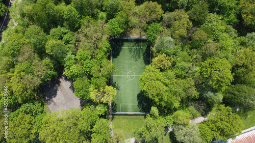 Aerial view of a football pitch between green trees on a sunny day in Kaunas