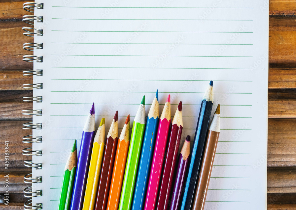 Color pencils and notebook on wooden table Color pencils and notebook on wooden table