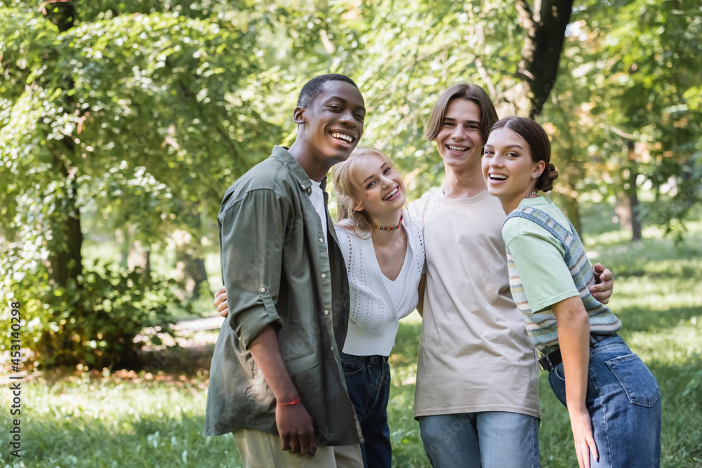 Multiethnic teenagers hugging and looking at camera in park Multiethnic teenagers hugging and looking at camera in park