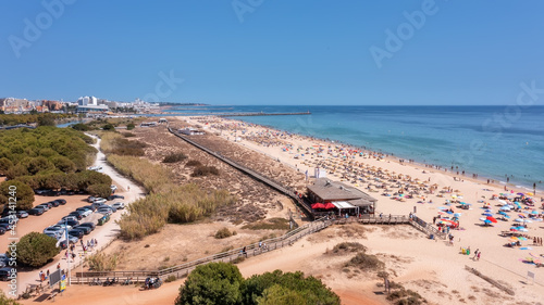 Aerial view of the luxury Falesia beach in Vilamoura. With sunbathing tourists on sun beds. Marina port with yachts, in the background. © sergojpg