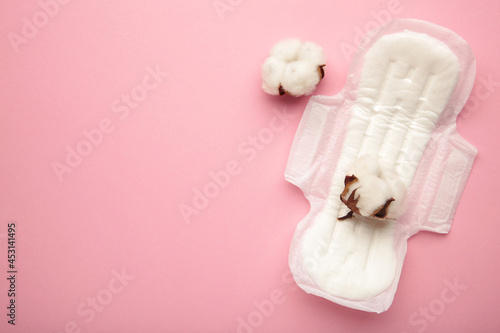 White sanitary pad  hygiene protection on a pink background. Gynecological menstrual cycle. A rose flower lies on a menstrual pad. First menstruation