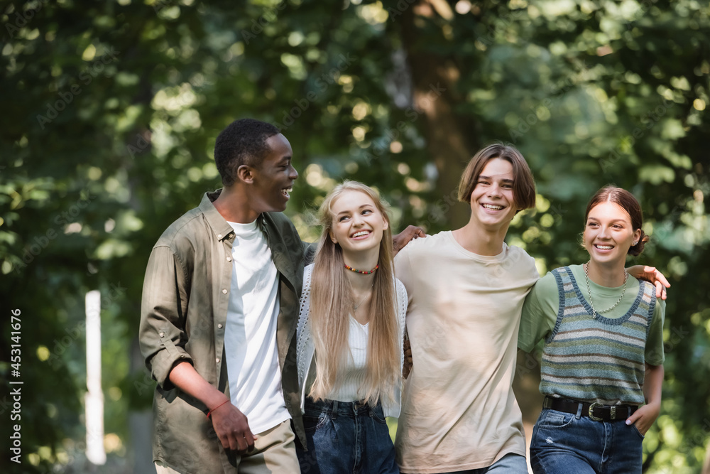 Cheerful multiethnic teenagers embracing in park Cheerful multiethnic teenagers embracing in park